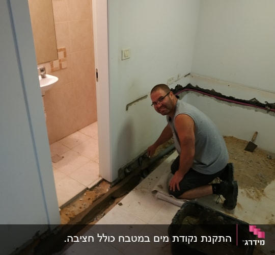 אדם עובד על צינור מים בקיר חדר אמבטיה